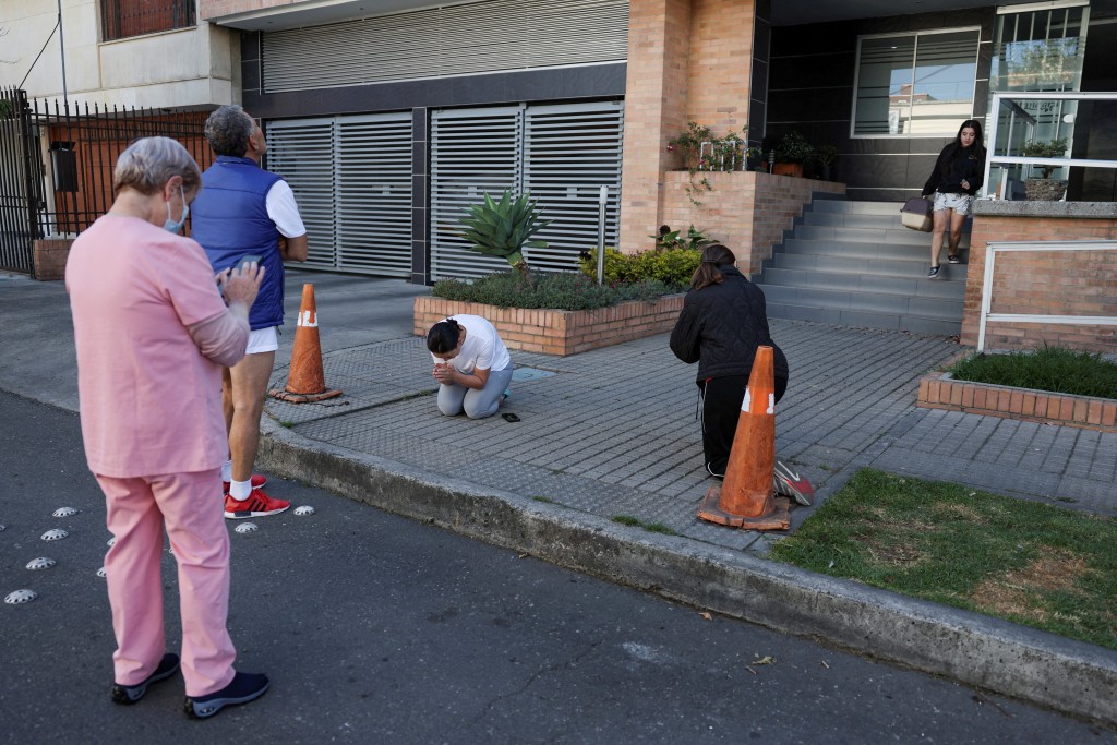 A woman prays as people gather outside a building following an earthquake in Bogota, Colombia, August 10, 2026. (Reuters)