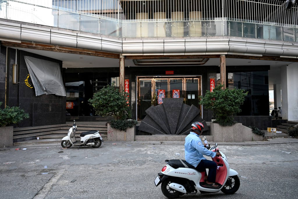 Photo by TANG CHHIN SOTHY / AFP  A man rides his motorcycle past the closed GC Casino in Sihanoukville on January 14, 2026.