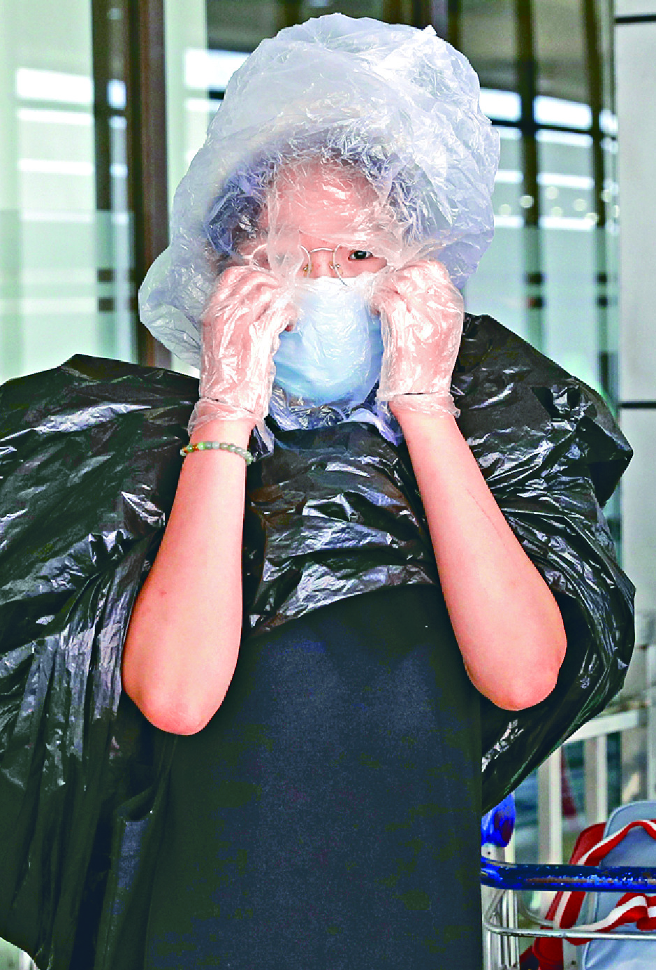 A traveler covers her head with a plastic bag and her body with a rubbish bag at Manila's international airport. AP A traveler covers her head with a plastic bag and her body with a rubbish bag at Manila's international airport. AP