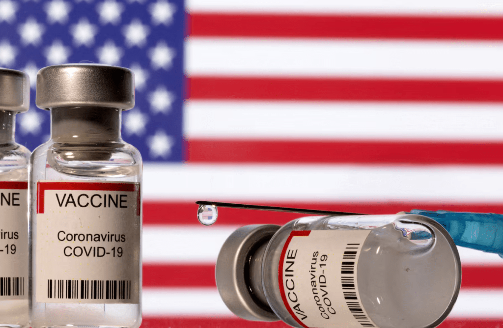 Vials labelled "VACCINE Coronavirus COVID-19" and a syringe are seen in front of a displayed U.S. flag in this illustration taken December 11, 2021. REUTERS/Dado Ruvic/Illustration