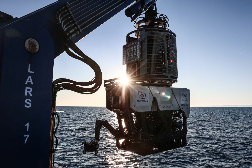 Photo by THIBAUD MORITZ / AFP  This photograph shows a view of the “ROV C 4000,” a remotely operated vehicle manufactured by the French company LD Travocean and designed for seabed exploration, emerges from the water to board the deck of the Jason (BSAA), chartered for an archaeological mission on the wreck of the CAMARA 4 off the coast of Ramatuel, in southeastern France on April 7, 2026.