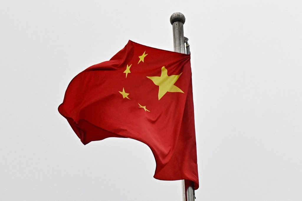 A Chinese flag flutters in the wind in a street surrounding the Great Hall of the People where the opening of the Chinese People's Political Consultative Conference (CPPCC) takes place, in Beijing on March 4, 2026. (Photo by Pedro PARDO / AFP)