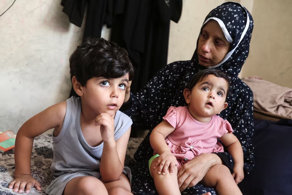 Displaced Palestinian cancer patient Khuloud Abu Sahmoud, 33, sits with her children at an UNRWA school where she is sheltering, in Khan Younis, in the southern Gaza Strip, August 8, 2026. REUTERS/Ramadan Abed