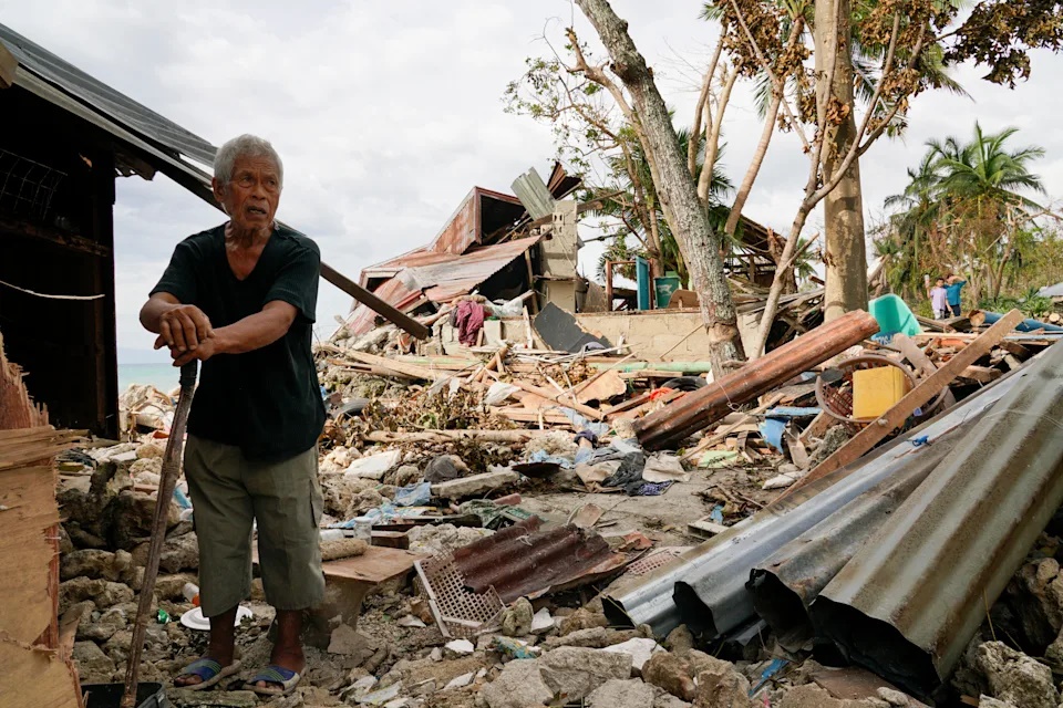 FILE -Bernardino Aspacio walks past rubbles from his damaged house due to Typhoon Rai in Alegria, Cebu province, central Philippines, Dec. 22, 2021. (AP Photo/Jay Labra, File)