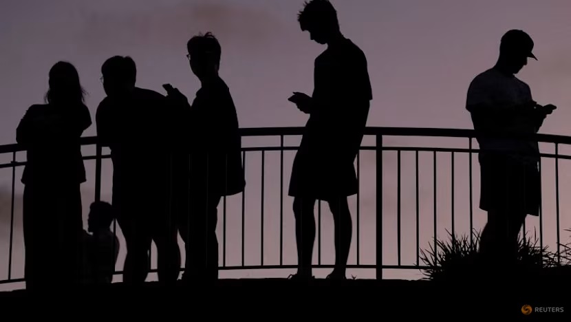  People use their mobile phones at dusk in Brisbane, Australia, December 8, 2025. REUTERS/Hollie Adams