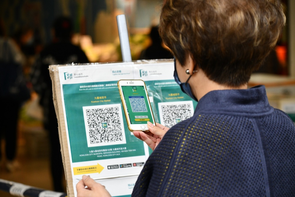 A woman scans the LeaveHomeSafe venue QR code before entering a market. File photo. A woman scans the LeaveHomeSafe venue QR code before entering a market. File photo.