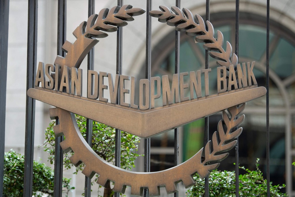 A woman walks past the logo of the Asian Development Bank (ADB) outside the bank's headquarters in Manila on April 15, 2025. (Photo by Ted ALJIBE / AFP)