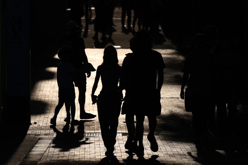 Photo by DAVID GRAY / AFP. People walk towards the floral tribute memorial as mourners gather in memory of victims of a shooting at Bondi Beach, in Sydney on December 20, 2025.