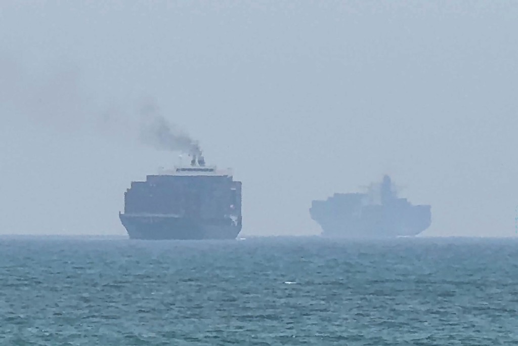 This frame grab taken from AFPTV video footage on July 12, 2026 shows cargo ships anchoring near the Strait of Hormuz off the eastern coast of the United Arab Emirates at Khor Fakkan. Tehran announced it was closing the Strait of Hormuz on July 12 and launched missiles and drones at its Gulf neighbours, in retaliation for new US strikes following an attack by Iranian forces on a merchant vessel that was abandoned in flames by its crew.
