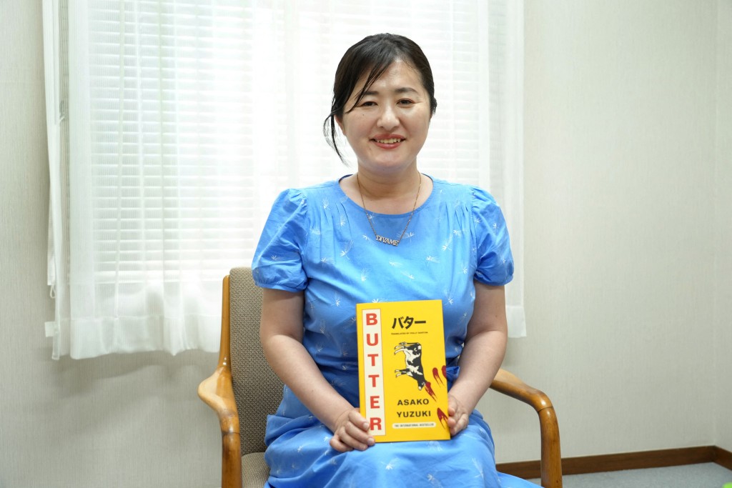 This photo taken on June 24, 2025 shows Japanese author Asako Yuzuki posing with her novel "Butter", translated into a foreign language, during an interview with AFP in Tokyo. (Photo by Kazuhiro NOGI / AFP)