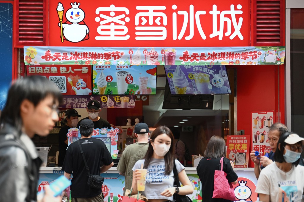 People walk past a Mixue Ice Cream & Tea store in Hong Kong on March 26, 2025.  AFP