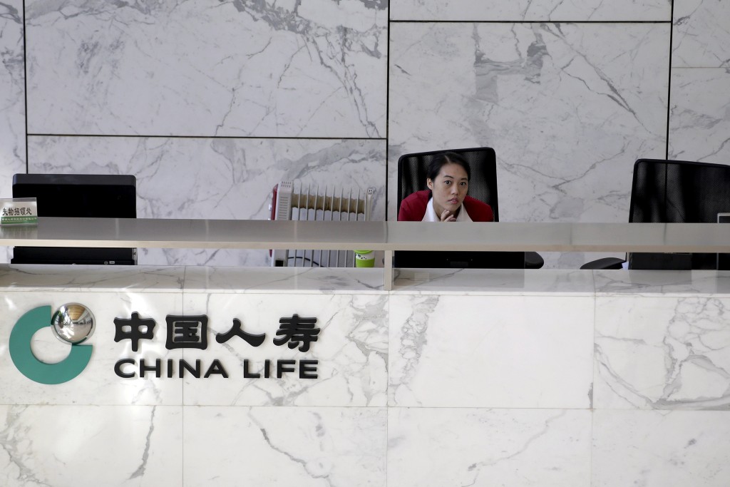 An employee sits at the reception of the headquarters building of China Life insurance in Beijing, China, March 24, 2016. REUTERS