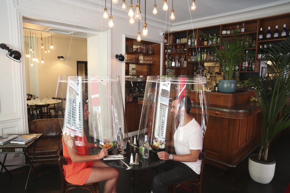 Dining under a plastic shield Wednesday, May 27, in a restaurant of Paris.