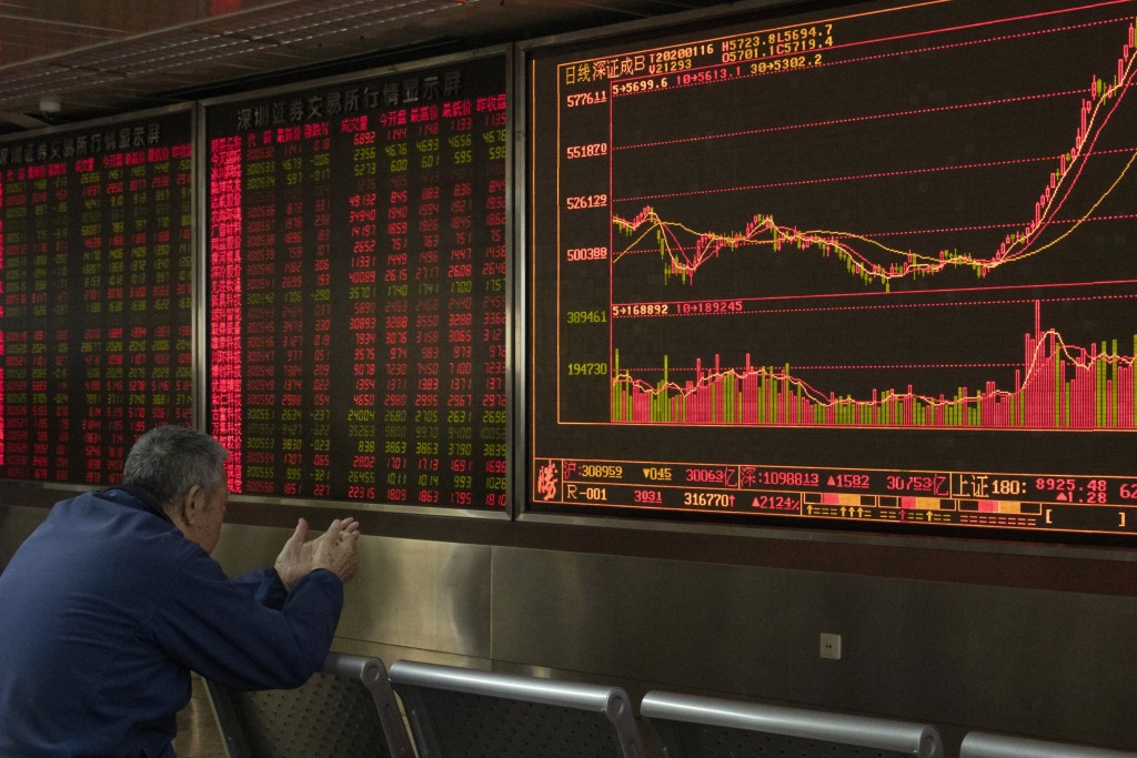 FILE - In this Jan. 16, 2020, file photo, an investor monitors stock prices at a brokerage in Beijing. AP