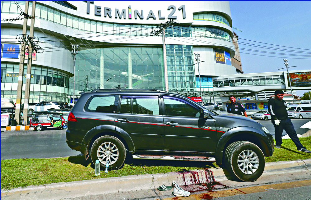 A pool of blood forms near a victim's vehicle and left-behind footwear as people, including monks, take videos and pictures outside the mall. AP
