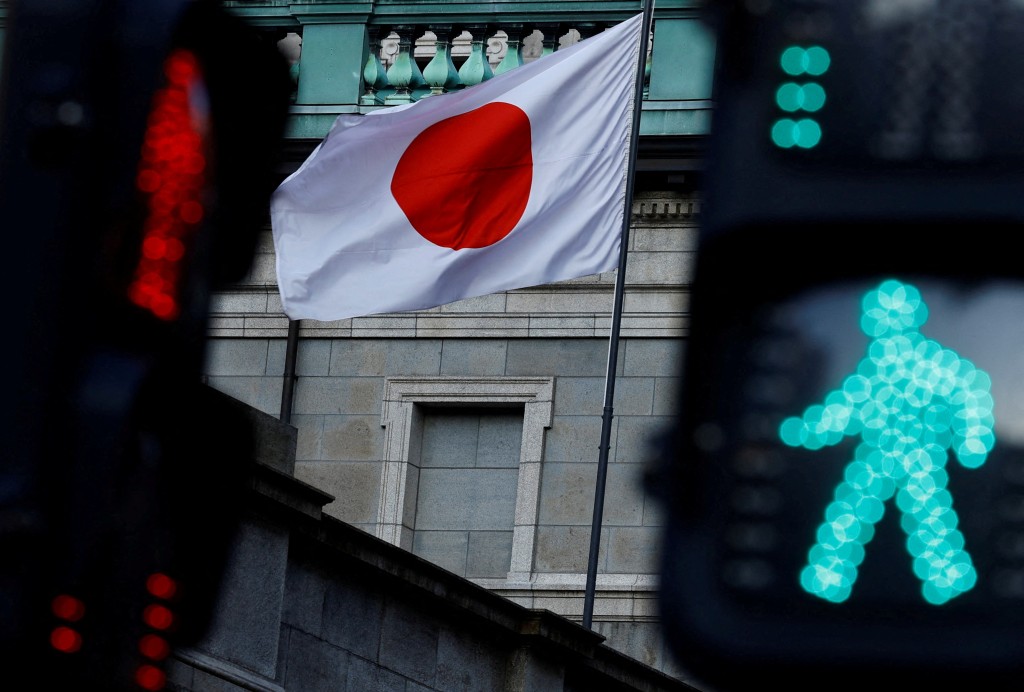 FILE PHOTO: Japanese national flag hoisted atop of the Bank of Japan headquarters building is seen between traffic signals in Tokyo, Japan January 23, 2025. REUTERS/Issei Kato/File Photo