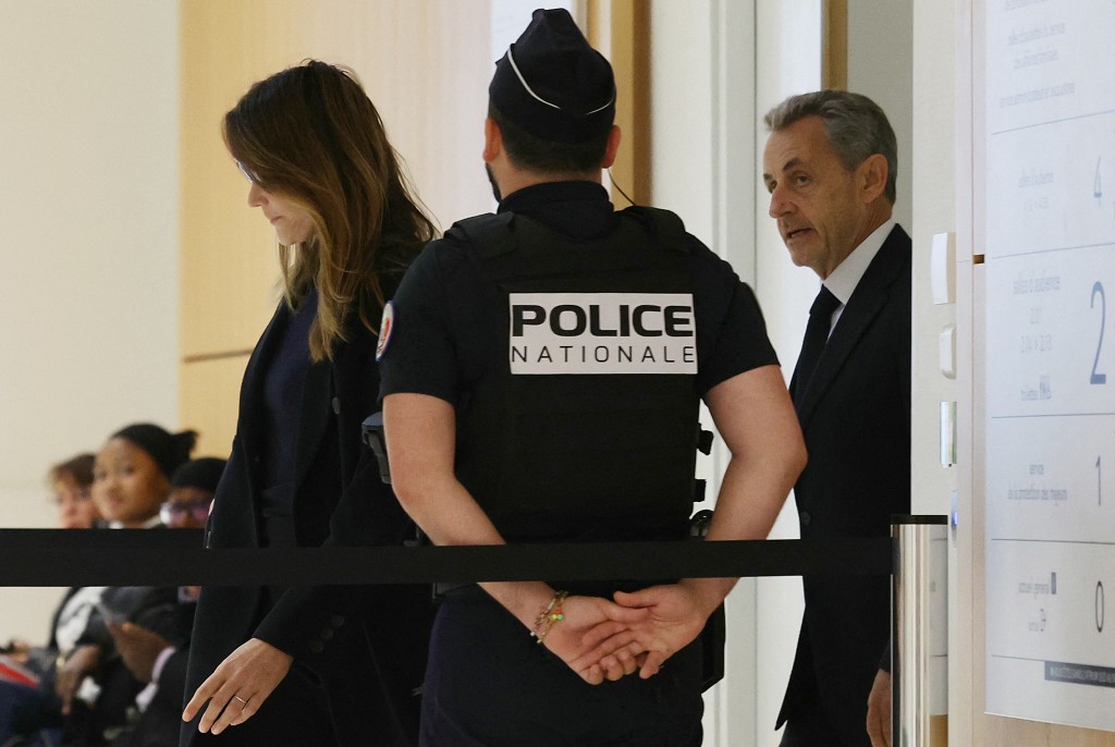  Former French president Nicolas Sarkozy (R) with his wife Carla Bruni (L) arrives for the verdict in his trial for illegal campaign financing from Libya for his successful 2007 presidential bid, at the Tribunal de Paris courthouse in Paris, on September 25, 2025.  (Photo by Alain JOCARD / AFP)