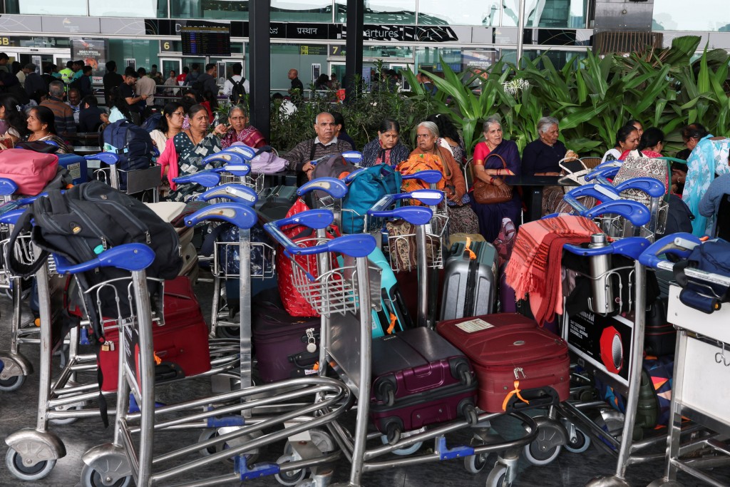 Travellers sit with their luggage at Kempegowda International Airport in Bengaluru, India, December 6, 2025. REUTERS/Priyanshu Singh