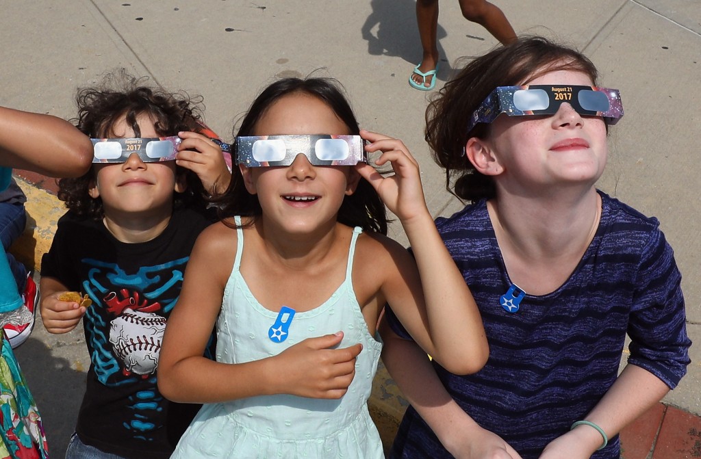 Photo by BRUCE BENNETT / GETTY IMAGES NORTH AMERICA / AFP  Spectators look skyward during a partial eclipse of the sun on August 21, 2017 at the Cradle of Aviation Museum in Garden City, New York.