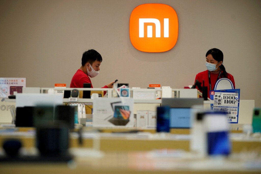 Staff members stand near the company logo at a Xiaomi store in Shanghai, China November 1, 2021. Picture taken November 1, 2021. REUTERS