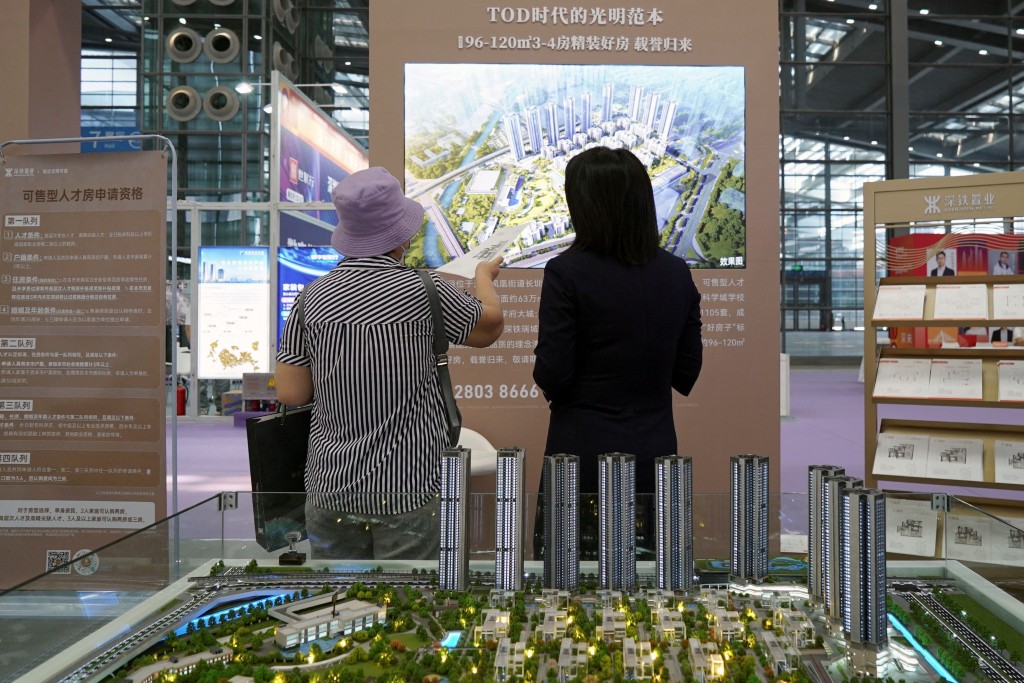 An agent attends to a customer near a scale model of residential buildings at a property fair in Shenzhen, Guangdong province, China October 12, 2024. REUTERS.