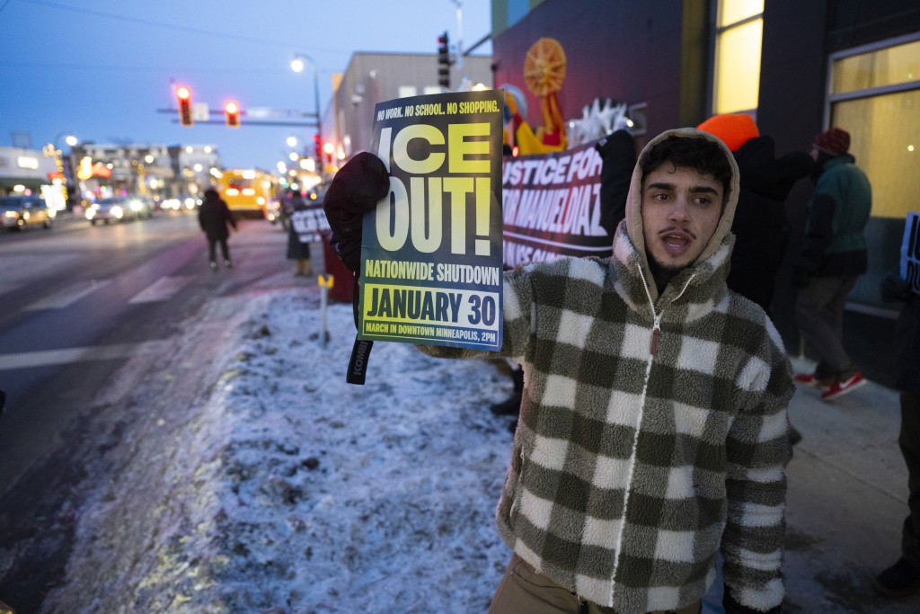 Photo by ROBERTO SCHMIDT / AFP  A protester holds a sign as he joins others to demand that federal immigration agents leave the city during a “Hands Off MN !