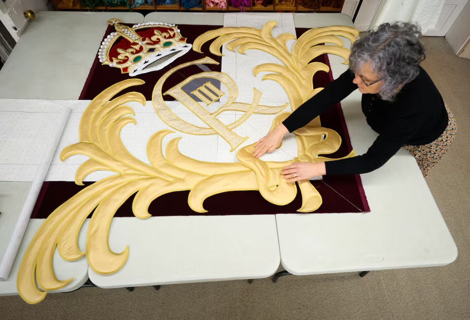 Studio manager Gemma Murray arranges embroidery pieces of a crown and the cipher of His Majesty King Charles III for the new Royal Opera House stage curtains at the Royal School of Needlework, based at Hampton Court Palace, ahead of their unveiling in May 2026, in London, Britain, March 4, 2026. REUTERS/Isabel Infantes 