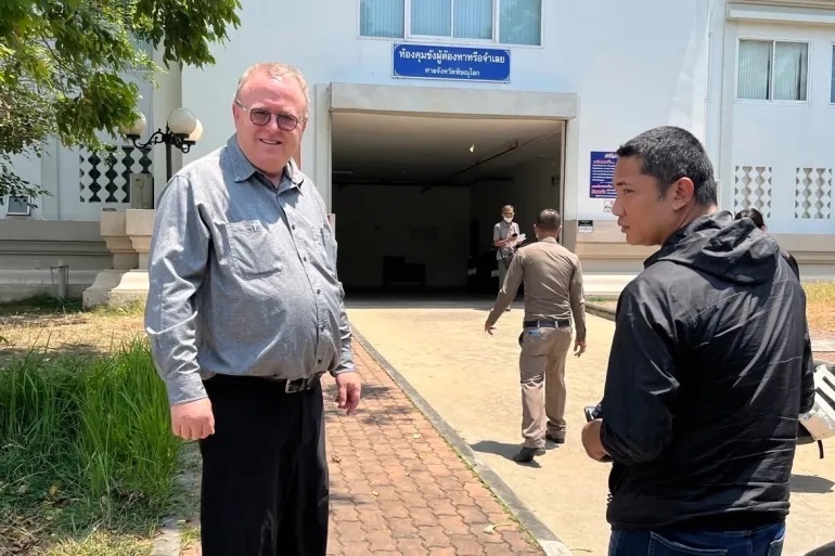 Paul Chambers, left, of Naresuan University, stands outside the police station in Phitsanulok, Thailand, where he was arrested on April 8, 2025, on charges of insulting the monarchy [AP Photo]