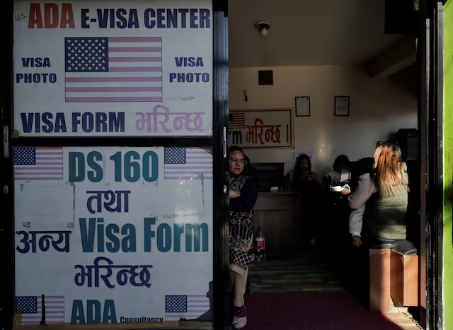 A woman holding a child waits to fill out a U.S. visa application form at a consultancy that assists with visa paperwork in Kathmandu, Nepal, November 28, 2025. REUTERS/Navesh Chitrakar