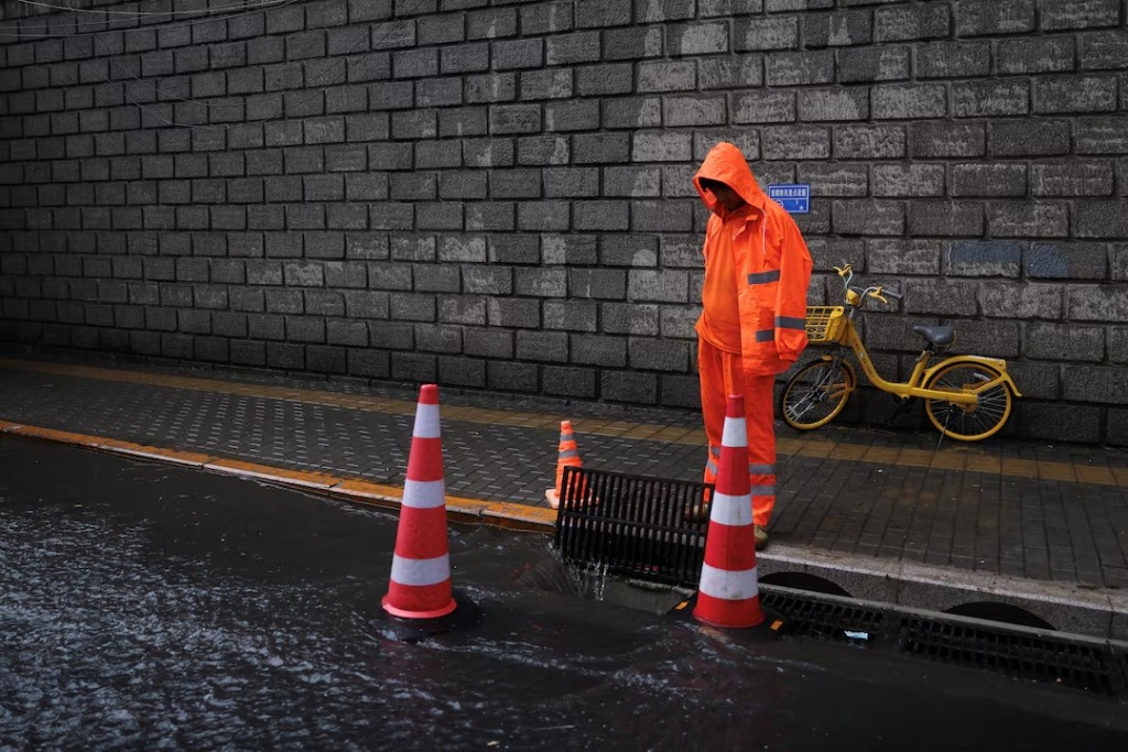 A worker monitors floodwaters being drained through sewer following a sudden rainfall,under the impact of Typhoon Dolphin, at Beijing's Central Business District (CBD) in Beijing, China August 11, 2026. REUTERS/Tingshu Wang 