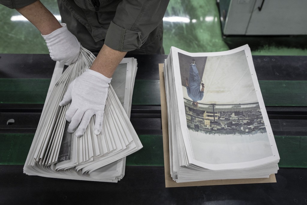 Photo by YUICHI YAMAZAKI / AFP  This picture taken on March 19, 2026 shows a staff member packing photographer Kazuma Obara’s work titled “The Newspaper” at the Kyoto Shimbun factory in Kumiyama, Kyoto prefecture.