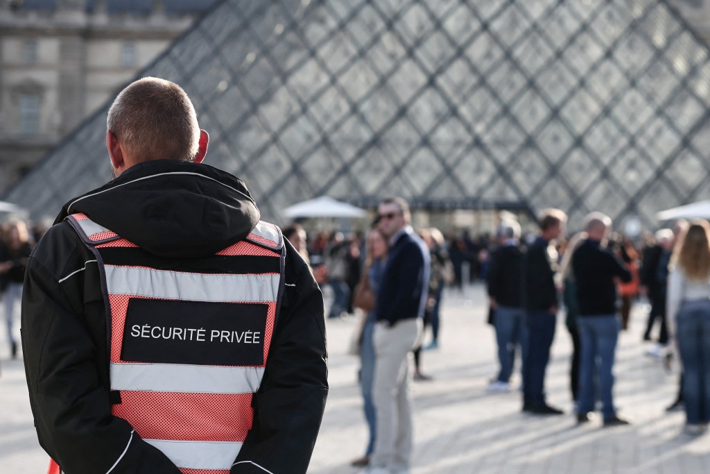 A security guard stands in front of the Pyramide du Louvre, with the Louvre Museum in the background in Paris on October 22, 2025. (AFP)