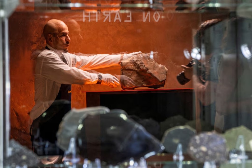 A handler is reflected on a showcase as he organizes meteorite NWA 16788, the largest known piece of Mars on Earth, during the press preview of Sotheby’s Natural History auction in New York City, U.S., July 8, 2025. REUTERS/Eduardo Munoz 