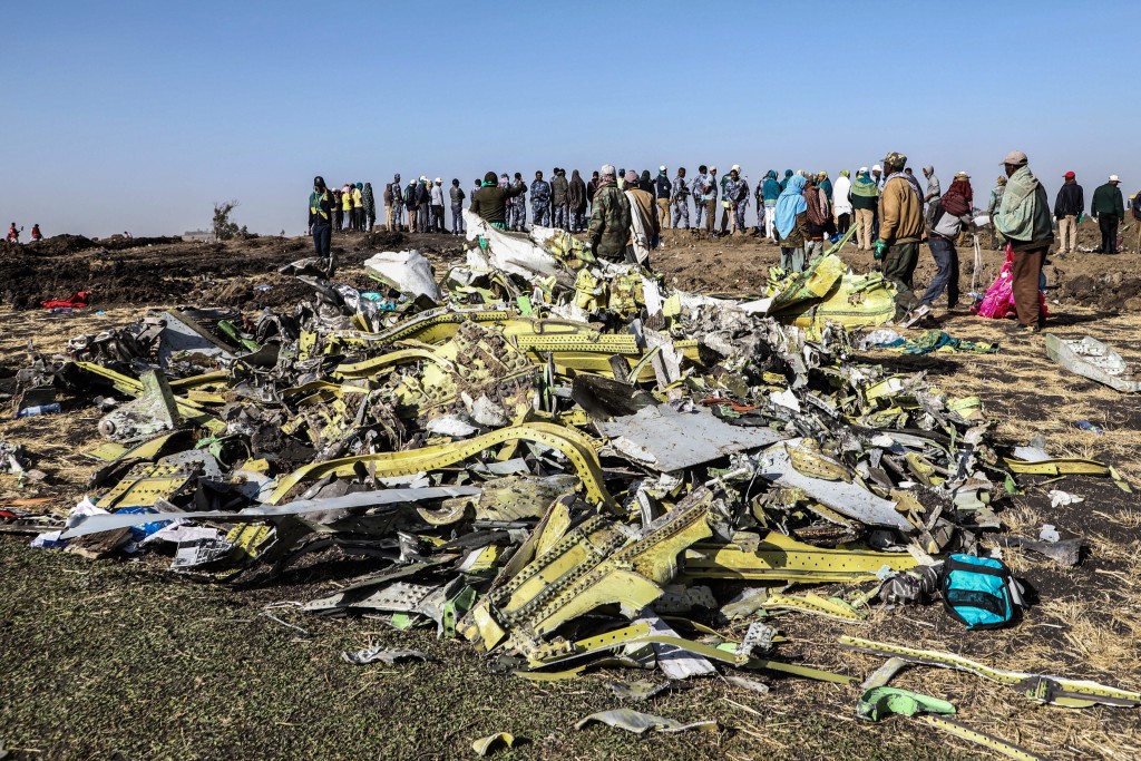 Photo by MICHAEL TEWELDE / AFP People stand near collected debris at the crash site of Ethiopia Airlines near Bishoftu, a town some 60 kilometres southeast of Addis Ababa, Ethiopia, on March 11, 2019.