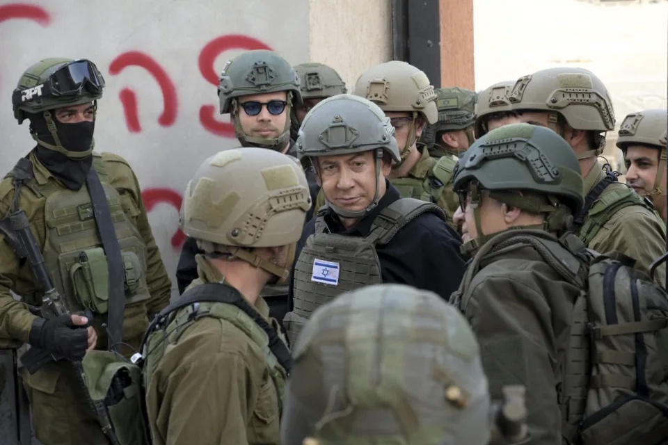 Israeli Prime Minister Benjamin Netanyahu, center, wears a protective vest and helmet as he receives a security briefing with commanders and soldiers in the northern Gaza Strip, on Monday, Dec. 25, 2023. (Avi Ohayon/GPO/Handout via AP) Israeli Prime Minister Benjamin Netanyahu, center, wears a protective vest and helmet as he receives a security briefing with commanders and soldiers in the northern Gaza Strip, on Monday, Dec. 25, 2023. (Avi Ohayon/GPO/Handout via AP)