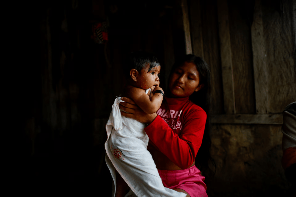  Edinizia Karo Munduruku poses for a picture with her daughter Ewayne Yoto, during a mission by researchers from the Brazilian public health institute Fiocruz to investigate health disorders among Munduruku Indigenous people that are potentially linked to mercury contamination caused by illegal gold mining, in Sai Cinza village, in the municipality of Jacareacanga, Para state, Brazil February 20, 2025. REUTERS/Adriano Machad