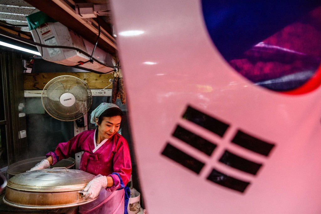 In this photo taken on October 7, 2025, Son Yun-kyung carries a steamer full of North Korean style mandu dumplings at her food store on Gyodong Island, roughly 2.3 kilometers from North Korea.  Photo by ANTHONY WALLACE / AFP