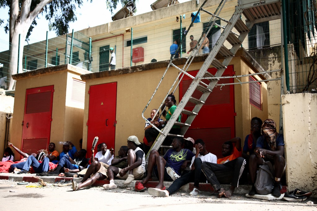 Migrants sit outside the CETI short-stay migrant centre in the Spanish North African enclave of Ceuta on August 1, 2026. (AFP)