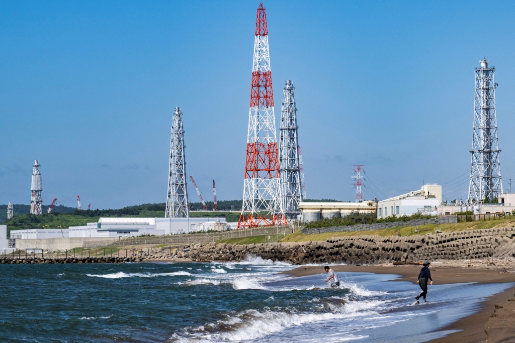 Photo by YUICHI YAMAZAKI / AFP  This picture taken on August 5, 2024 shows people visiting Arahama beach in front of the Kashiwazaki-Kariwa nuclear power station in Kashiwazaki, in Japan's Niigata prefecture.