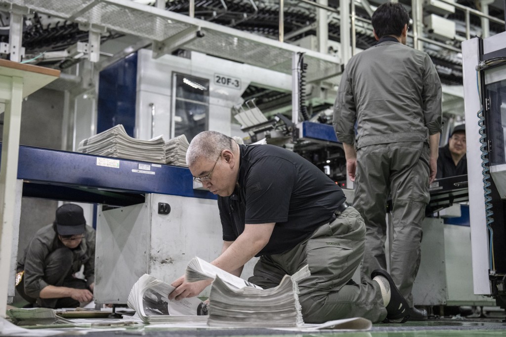 Photo by YUICHI YAMAZAKI / AFP  This picture taken on March 19, 2026 shows staff members inspecting the printing quality at the Kyoto Shimbun factory in Kumiyama, Kyoto prefecture.
