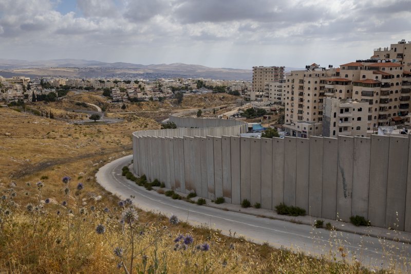 In this Friday, June 19, 2020 photo, a the Shuafat refugee camp is seen behind section of Israel's separation barrier in Jerusalem. For years, Israel’s harshest detractors have labeled it an apartheid state. In this Friday, June 19, 2020 photo, a the Shuafat refugee camp is seen behind section of Israel's separation barrier in Jerusalem. For years, Israel’s harshest detractors have labeled it an apartheid state.