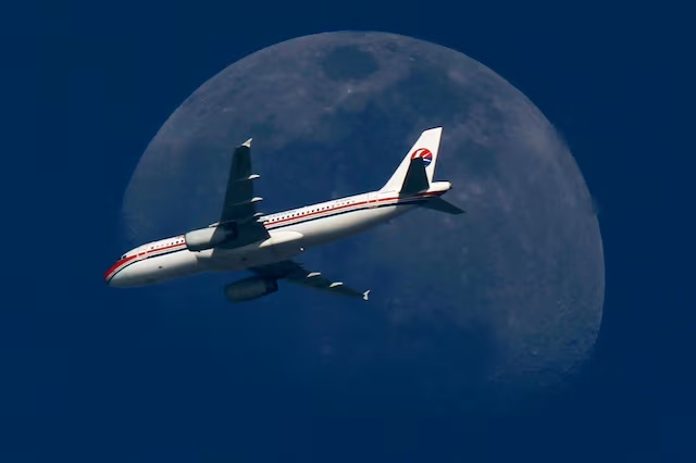 A China Eastern Airlines passenger jet passes in front of the moon over Shanghai May 13, 2011. REUTERS/Aly Song/File Photo 