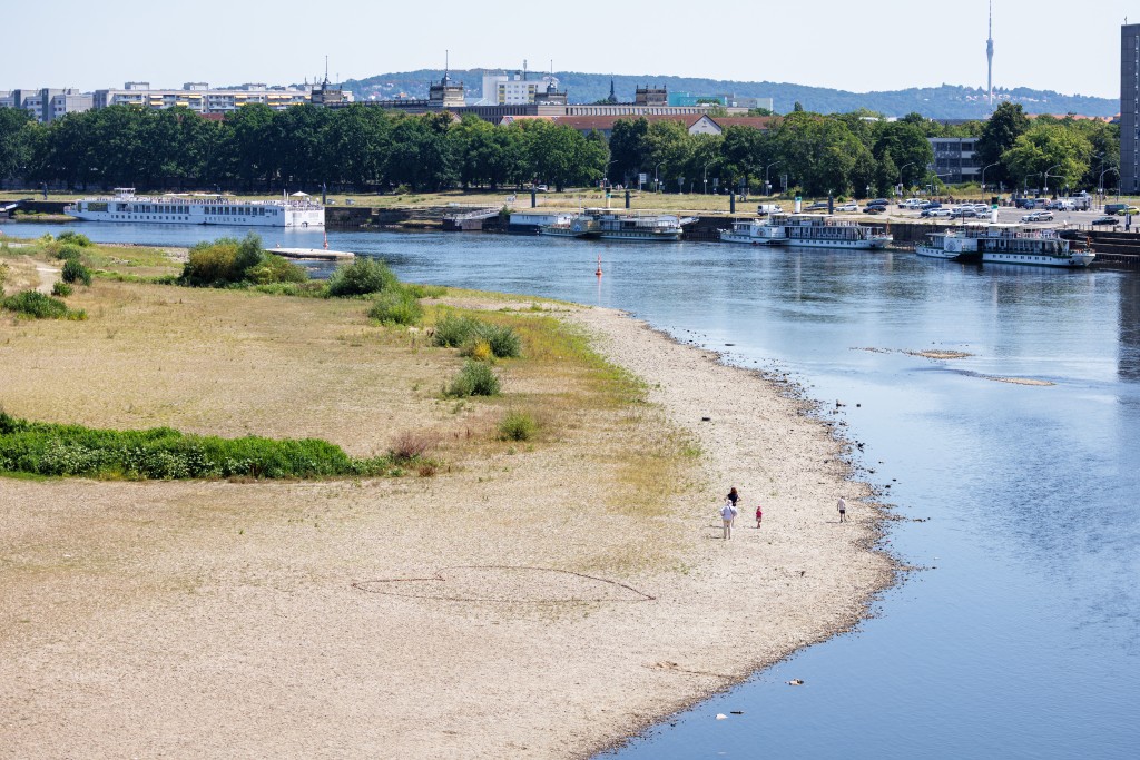 People walk on the long riverbed of the river Elbe, as a heart is drew on the ground in Dresden, eastern Germany, on August 9 (AFP)
