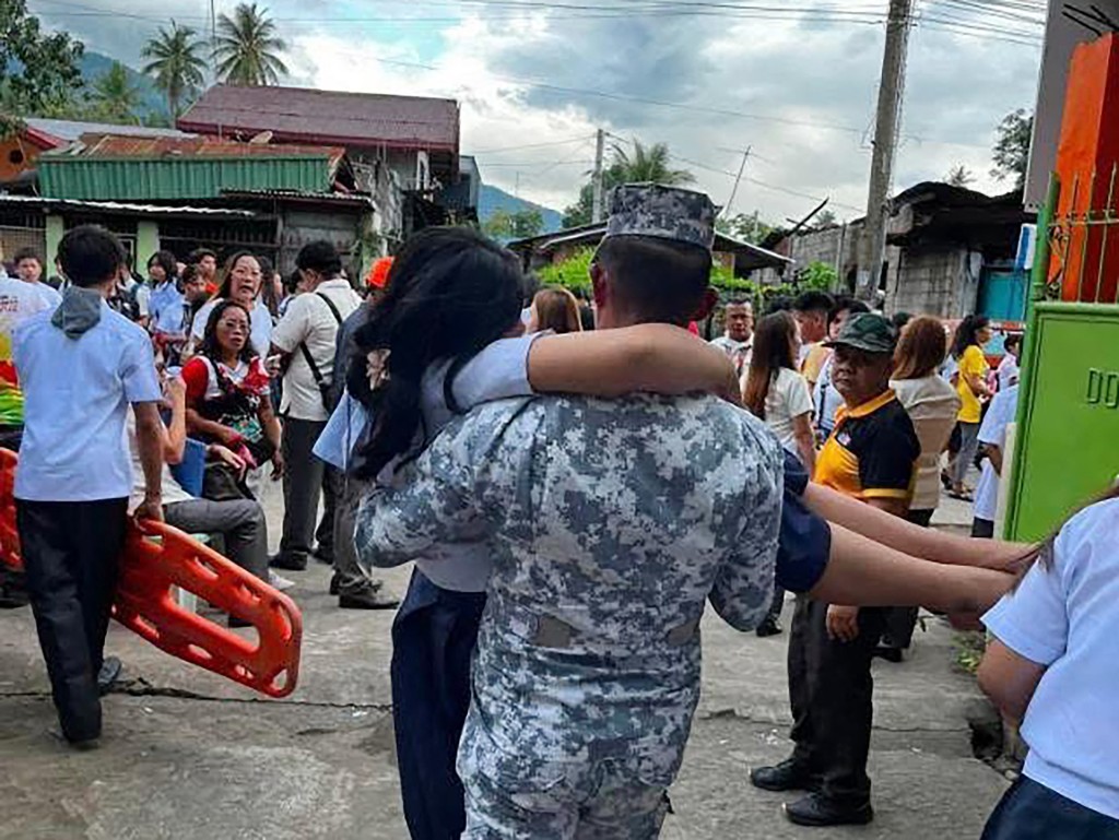 A Coast Guard serviceman carrying an earthquake-affected student in Sta Cruz, Davao del Sur. (AFP)