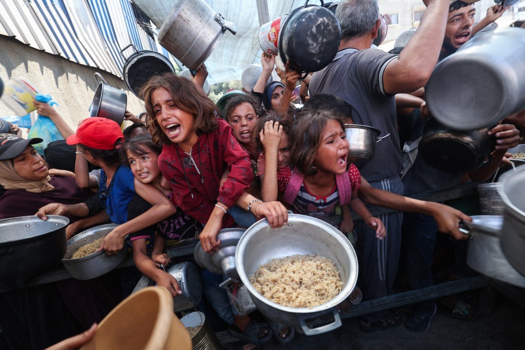  Palestinians shove to receive a hot meal from a charity kitchen in the Nuseirat refugee camp in the Israel-besieged Gaza Strip on September 4, 2025, where the UN has declared famine after nearly two years of war. (Photo by Eyad BABA / AFP)