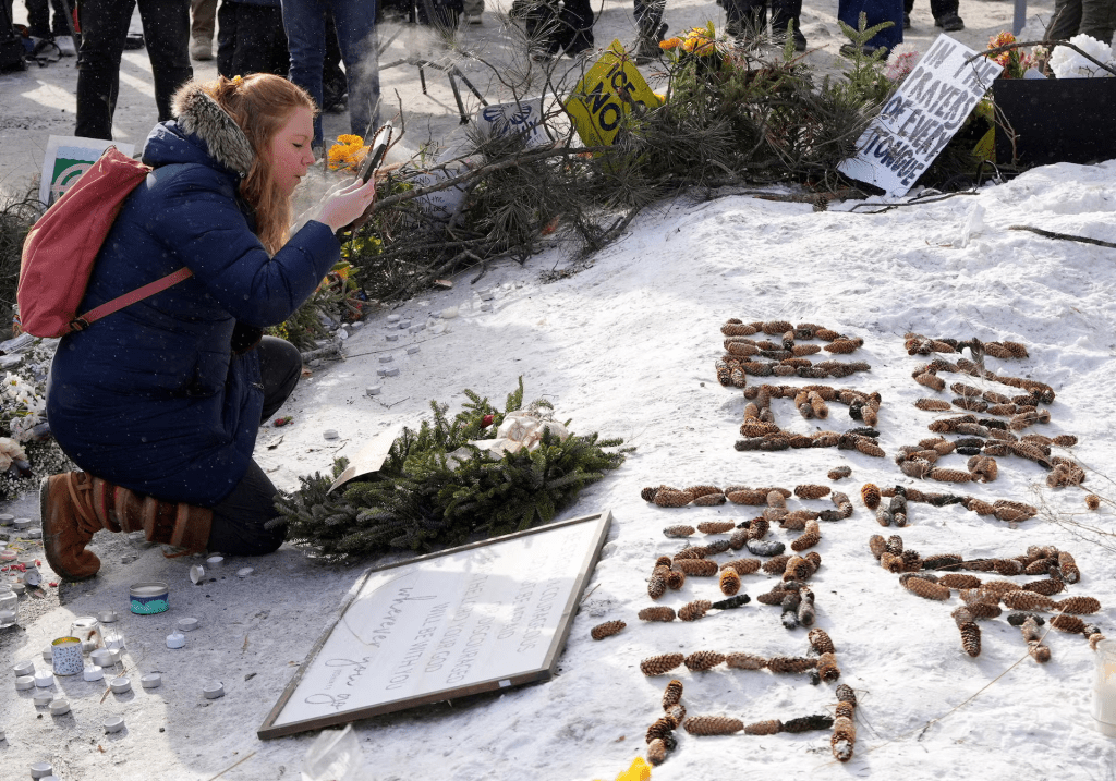 A woman clears snow from a picture of Alex Pretti at a makeshift memorial at the site where a man identified as Pretti was fatally shot by federal immigration agents trying to detain him, in Minneapolis, Minnesota, U.S. REUTERS/Tim Evans 