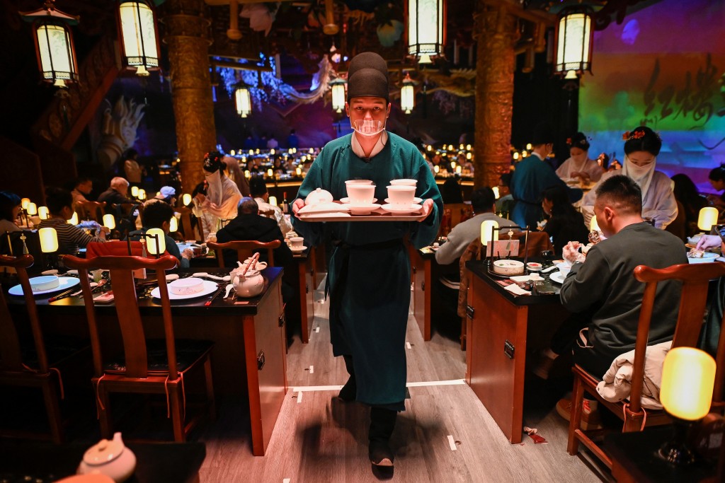 Photo by WANG ZHAO / AFP  This picture taken on November 5, 2025 shows a waiter in traditional Chinese clothes serving meals at a theatrical restaurant in Beijing.