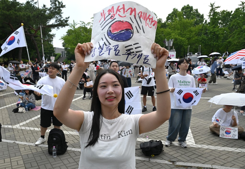 Photo by JUNG YEON-JE / AFP  South Korean protesters wave the national flags outside a vote-counting centre in Seoul on June 10, 2026, to call for a rerun of the local elections due to a shortage of ballot papers.