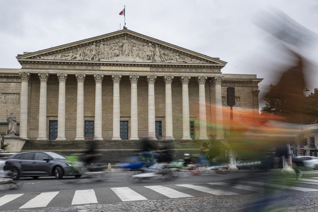 This photograph shows traffic in front of of the French National Assembly building in Paris on October 6, 2025. Almost simultaneously with the announcement of France's Prime Minister's resignation, the president of the National Rally, called on the French President to dissolve the National Assembly and call for new early legislative elections. (Photo by Martin LELIEVRE / AFP)