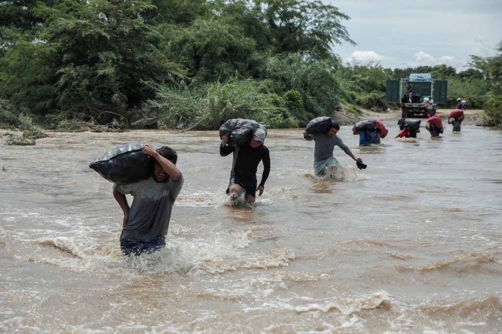 Residents carry sacks of vegetables through a stream flooded by the rains caused by the direct influence of Cyclone Yaku, in Piura, Peru March 11, 2023. REUTERS/Sebastian Castaneda/File Photo 